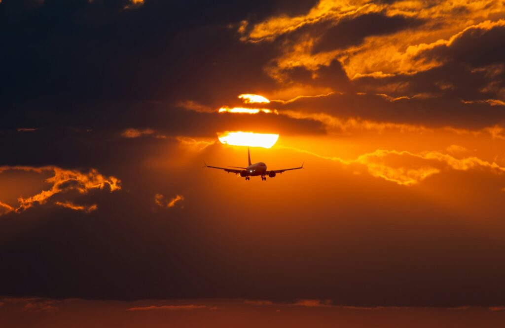 a plane flying in the sky at sunset